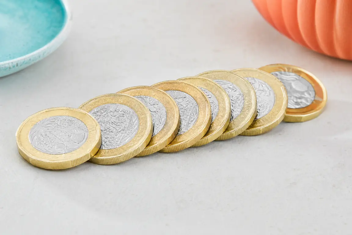 Pound coins fanned out across a pale surface.