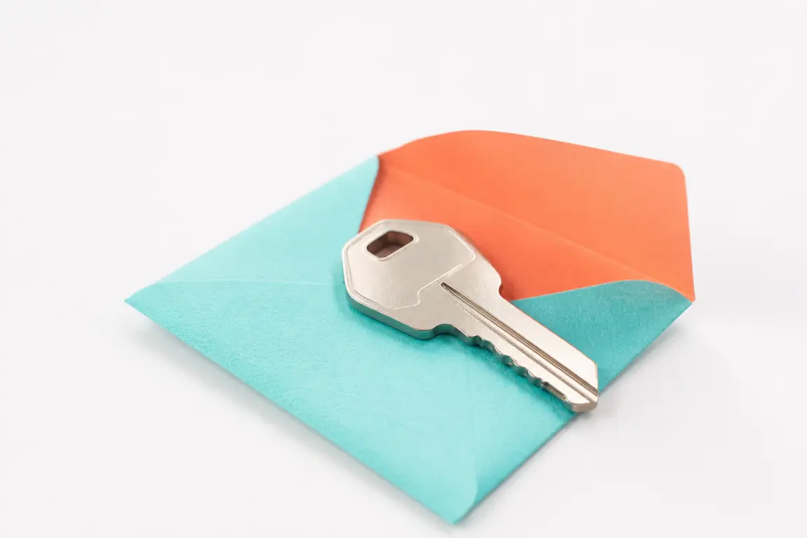 A plain unmarked machine key resting in an open paper sleeve.