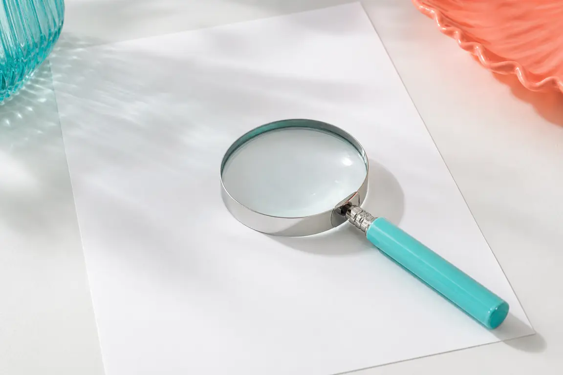 A magnifying glass resting on a blank sheet of paper.